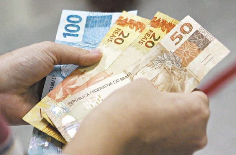 Homem com cédulas de real nas mãos